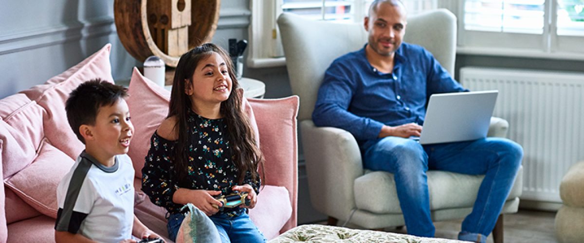 Brother and sister on sofa playing on games console, competition, weekend activities, mature man working from home